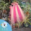 A plant grow light with multiple heads illuminates a collection of potted plants in a garden setting. Produktbild-Vorschau