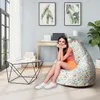 A woman is sitting on a floral patterned bean bag chair in a bright, modern room with a desk and window. Náhľad obrázku produktu