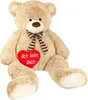 A large, beige teddy bear sitting down, holding a red heart with text on it. Náhled obrázku produktu