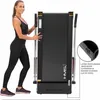 A woman is pushing a folded treadmill, demonstrating its compact storage. Voir les images du produit