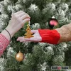 Two people decorating a Christmas tree, one holding a gingerbread ornament. Produktbild-Vorschau