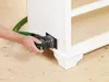 A person is using a sander with a vacuum hose attached to a white cabinet. Produktbild-Vorschau