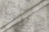 A roll of grey concrete-patterned adhesive film lies diagonally on a surface with a similar pattern. Produktbild-Vorschau