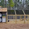 A chicken coop with a black and white coop house and a fenced-in run with straw and a chicken. Náhled obrázku produktu