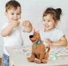 Two children are playing with a Scooby-Doo plush toy on a table. Náhled obrázku produktu