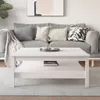 A white coffee table in a living room setting with a sofa and pillows in the background. Náhľad obrázku produktu