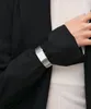 A close-up shot of a person's arm wearing a silver watch. Voir les images du produit