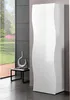 A modern white wardrobe with a wavy design stands next to a large window overlooking a garden. Produktbild-Vorschau