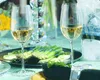 A table setting with two glasses of white wine, asparagus, and a bucket of ice with a bottle. Produktbild-Vorschau