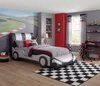 A child's bedroom decorated with a race car theme, featuring a race car bed, racing-themed bedding, curtains, and a rug. Produktbild-Vorschau