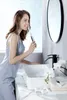 A woman is brushing her teeth in a modern bathroom. Náhled obrázku produktu