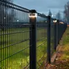 A black metal fence with solar-powered lights on top, extending into the distance along a grassy area. Voir les images du produit