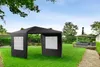 A black gazebo or party tent is set up on a green lawn in a backyard. In the background, there is another gazebo with outdoor furniture, a house, and trees. The sky is blue with some clouds. Produktbild-Vorschau