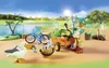 A Playmobil figure with a cart and bicycle near a body of water, with a pelican in the foreground. Podgląd zdjęcia produktu