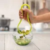 A hand holding a green avocado tool over a bowl of chopped avocado. Produktbild-Vorschau