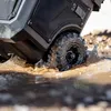 A close-up shot of a rugged, black wheel of a tool case splashing through muddy water. Náhled obrázku produktu
