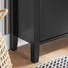 A close-up view of the black legs and bottom of a cabinet, with a woven basket and part of a rug visible. Náhľad obrázku produktu
