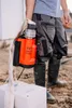 A person in work clothes and boots holds an orange drainage pump with a hose attached. Anteprima dell’immagine prodotto