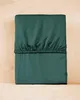 A folded green fitted sheet is placed on a light brown wooden surface. Náhled obrázku produktu