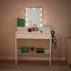 A white vanity table with a lighted mirror, makeup, and hair dryer. Produktbild-Vorschau