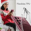 A woman in a Christmas sweater and hat is holding a pink smartphone, with a clear phone case shown next to it. Produktbild-Vorschau