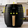 A black and gold air fryer with a digital display and control buttons, set against a kitchen background. Produktbild-Vorschau