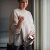 A woman is holding a black power bank with a white light on top, and a dark gray handbag. Produktbild-Vorschau