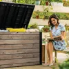 A woman is reading a book next to an open storage box in a garden setting. Produktbild-Vorschau