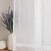 A close-up view of a white sheer curtain with embroidered wavy patterns and beads, next to a vase of lavender. Produktbild-Vorschau