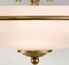 A close-up view of a ceiling lamp with a white glass shade and brass metal accents. Produktbild-Vorschau