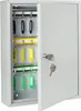 A light gray metal key cabinet with its door open, revealing multiple hooks for keys. Some keys with yellow and green tags are visible. Produktbild-Vorschau