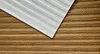 A close-up view of textured wall panels, with a portion of white ribbed panels overlapping the brown wood-grain textured panels. Produktbild-Vorschau