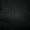 A close-up view of a black quilted fabric with a geometric triangle pattern. Produktbild-Vorschau