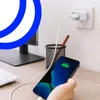 A smartphone is being charged by a wall adapter plugged into an outlet, with a computer keyboard and monitor in the background. Anteprima dell’immagine prodotto