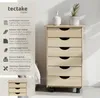 A wooden roll container with drawers is shown next to a bed, with decorative items on top. Text describes its features. Náhled obrázku produktu