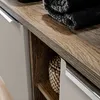 A close-up view of a bathroom vanity cabinet, showing the wood grain texture of the countertop and a folded black towel. Produktbild-Vorschau
