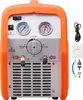 A front view of a portable refrigerant recovery machine with gauges, a selector dial, and input/output ports. Accessories and a manual are visible to the right. Podgląd zdjęcia produktu