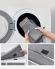 A person is putting a gray fabric item into a washing machine. Náhled obrázku produktu