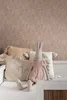 A stuffed bunny sits on a bed with pillows. Podgląd zdjęcia produktu