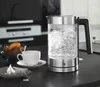 A glass kettle boiling water on a kitchen counter, with a cup of tea and fruit in the background. Anteprima dell’immagine prodotto
