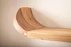 A close-up view of a wooden shelf with a curved end, mounted on a textured wall. Voir les images du produit