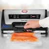 A person's hand is shown using a vacuum sealer to package a piece of salmon. Produktbild-Vorschau