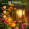 A solar garden light is shown in a garden setting with flowers and rain. Produktbild-Vorschau
