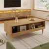 A living room scene featuring a wooden coffee table with items on it, placed on a patterned rug in front of a media console and a television. Produktbild-Vorschau