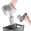 A hand is emptying dust from a vacuum cleaner dustbin into a trash bin. Another hand is holding a filter. Produktbild-Vorschau
