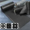 Several rolls of black perforated rubber matting are displayed on a gray tiled floor. In the foreground, a smaller inset shows three different types of black rubber connectors or feet. Podgląd zdjęcia produktu