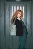 A woman stands in front of a dark green door, holding a gray tote bag. Náhľad obrázku produktu
