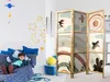 A child is lying on a bed in a room decorated with space-themed wall decals. A room divider is placed next to the bed. Náhled obrázku produktu