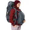 A woman wearing a red beanie and jacket is modeling a large hiking backpack with a smaller backpack attached to the front. Produktbild-Vorschau