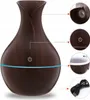 A dark wood-grain aroma diffuser with a blue light ring, shown with close-up views of its top, power button, and USB cable. Produktbild-Vorschau